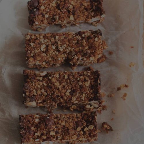 Granola bars on a cutting board with a knife.