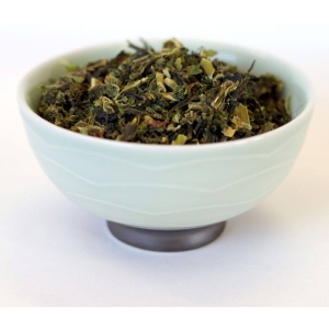 Green tea in a bowl on a white surface.