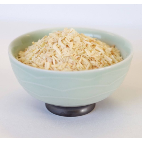 A bowl of shredded carrots on a white surface.