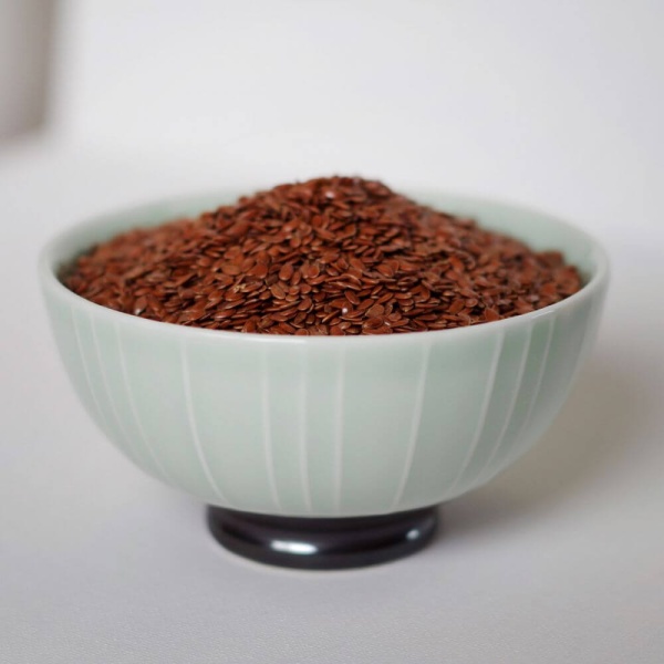 Flax seeds in a bowl on a white surface.