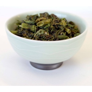 Green tea in a bowl on a white surface.
