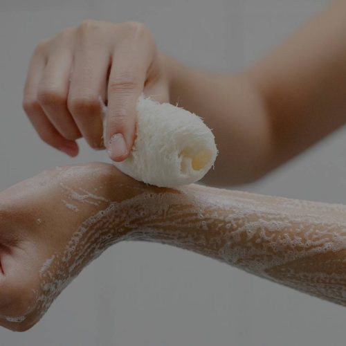 A woman is practicing sanitation by washing her arm with soap.