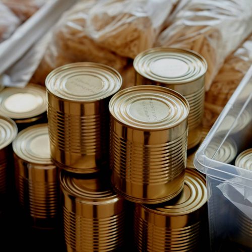 A group of cans on a table, part of building a 1-year food and water storage for your family.