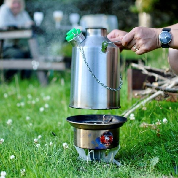 A person pouring water into a kettle for emergency food storage on a camping stove.