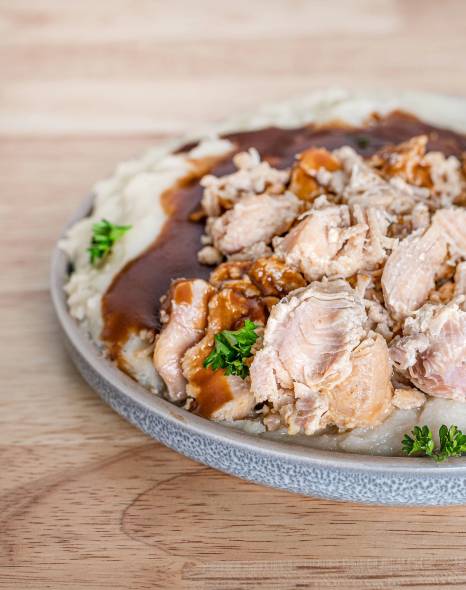 A plate of chicken and mashed potatoes on a wooden table used for emergency food storage.