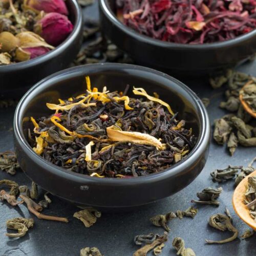 Four bowls of different types of tea on a table, providing a complete guide to store tea the right way.